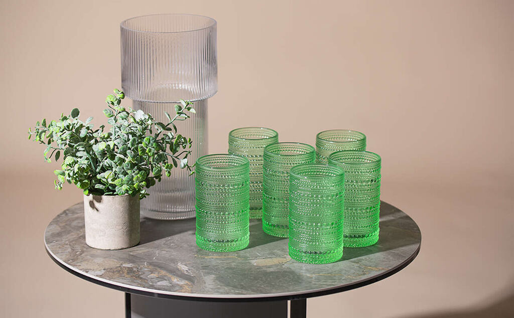tipos de copos em uma mesa ao lado de um vaso de planta e item decorativo
